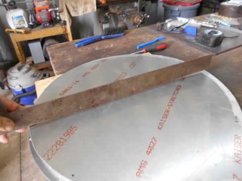 1992 Ford Bronco - A person's hand is holding a metal ruler against a large circular piece of metal with red text printed on it. The metal piece appears to be…