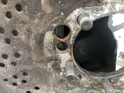 1995 Ford Bronco - A close-up view of a rusty metal component with several circular holes and threaded studs. The part appears to be from a vehicle's drivetra…