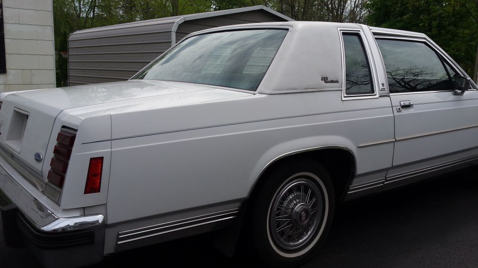 White 1986 Ford Crown Victoria rear quarter panel with chrome trim and vinyl roof.