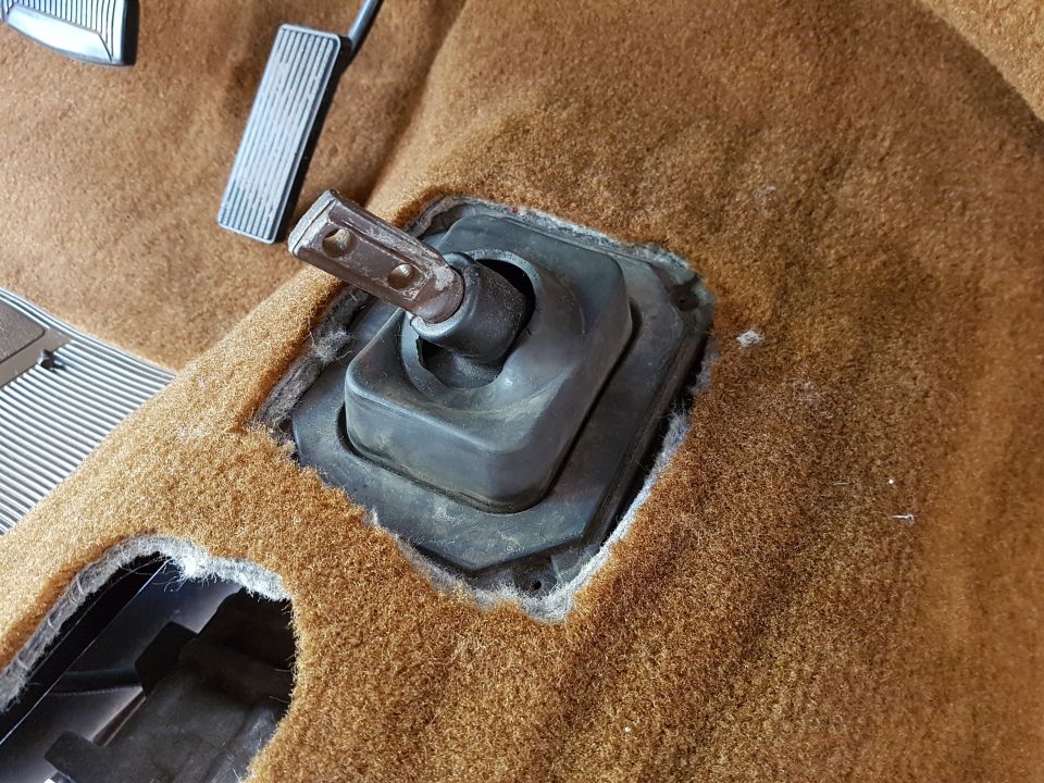 Close-up of car floor showing pedals and a removed shifter boot