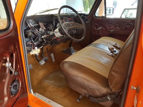 1978 Ford Bronco - The interior of an orange truck is shown with the dashboard in a state of disassembly, revealing wiring and internal components.