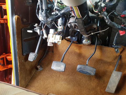 1978 Ford Bronco - Interior view of the footwell in a 1978 Ford Bronco, showing the pedals and extensive wiring harness.