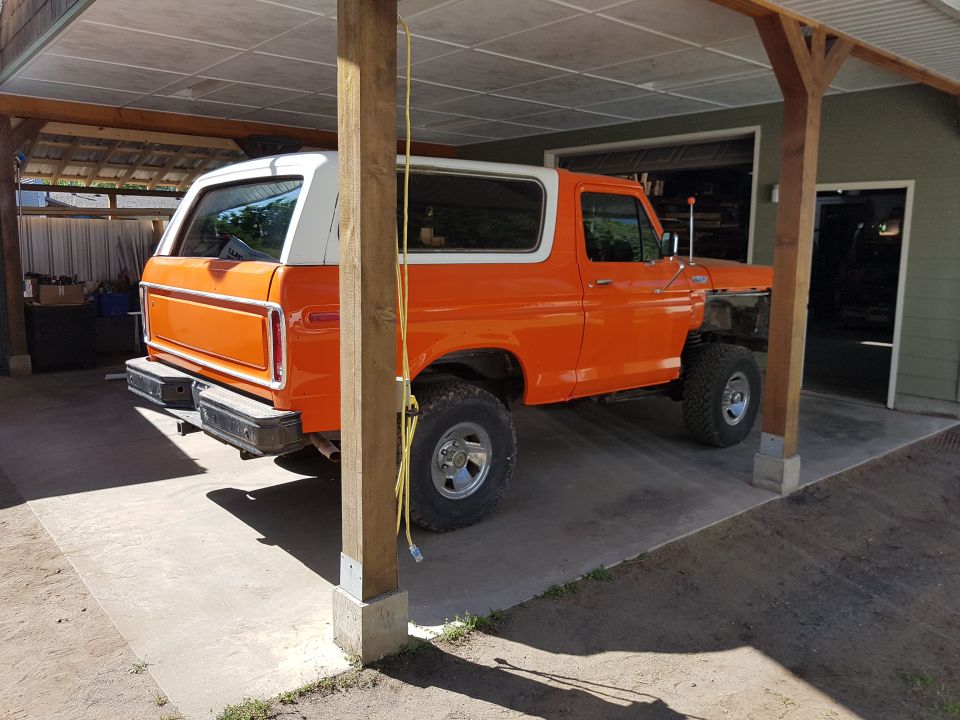 Orange SUV parked under a carport, front end is partially disassembled