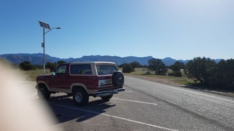 1985 Ford Bronco - 1985 Ford Bronco parked near a solar-powered light post with a scenic mountain backdrop.