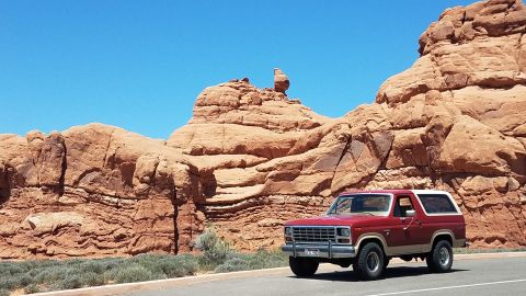 1985 Ford Bronco - 1985 Ford Bronco parked by sandstone formations under a clear blue sky.