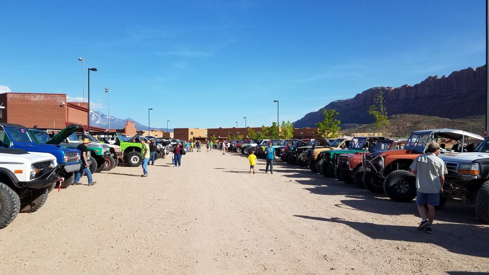 Line of off-road vehicles parked outside buildings with mountains in background
