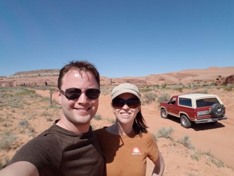1985 Ford Bronco - A couple poses for a photo with a red Ford Bronco in a desert setting.