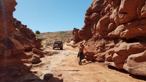 1985 Ford Bronco - A red Ford Bronco navigates a rocky canyon road under a clear blue sky.