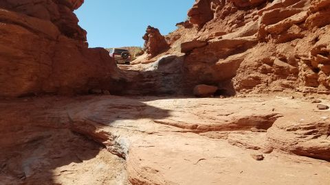 1985 Ford Bronco - A 1985 Ford Bronco navigates a challenging off-road path through a desert canyon.