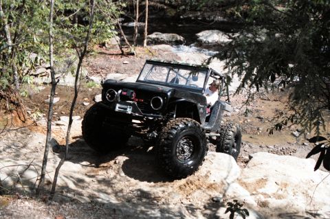 1976 Ford Bronco - Modified 1976 Ford Bronco navigating a rocky stream bed during an off-road excursion.