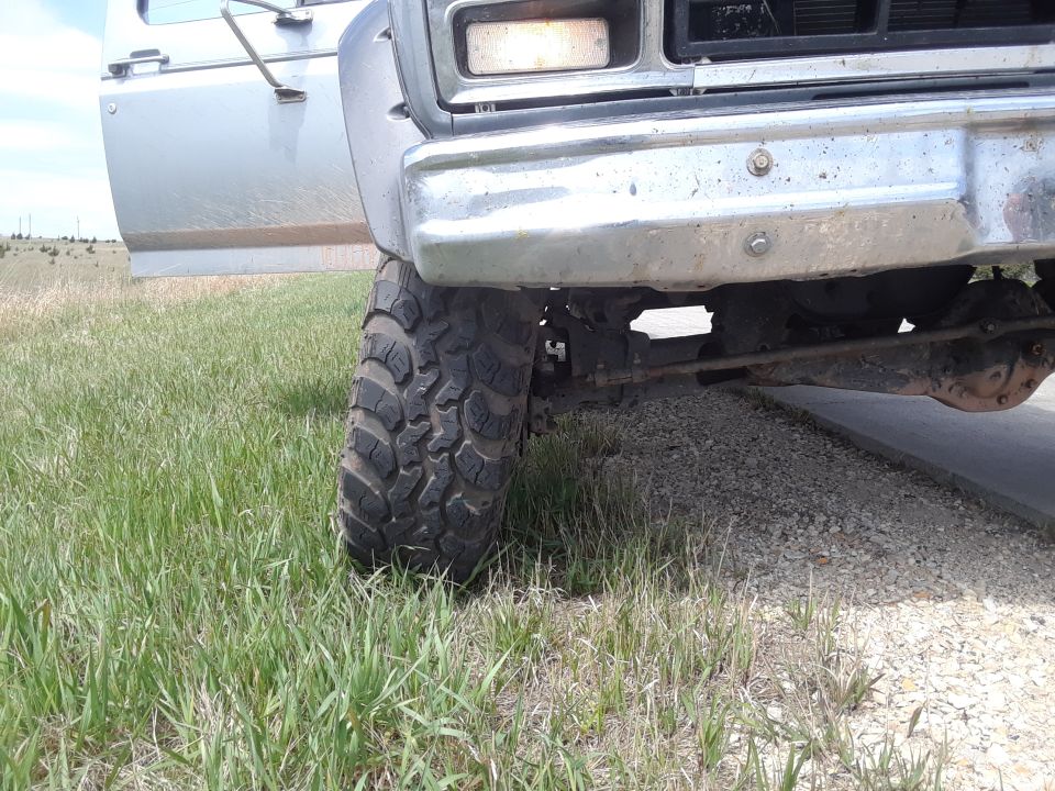 Front tire and bumper of a truck, door open. Appears to be from the 1980s