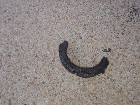 1985 Ford Bronco - A worn rubber component lies on a concrete surface, showing signs of damage.