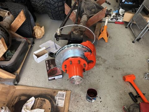 1992 Jeep Wrangler - A vehicle's front axle assembly is shown with new brake components laid out on the garage floor.
