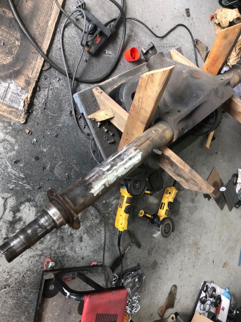 1992 Jeep Wrangler - A vehicle's axle assembly is shown on a workshop floor, supported by wood and surrounded by tools.