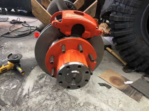 1992 Jeep Wrangler - Close-up of an orange brake caliper and rotor assembly, likely for a heavy-duty vehicle, with a large hub and multiple lug studs.