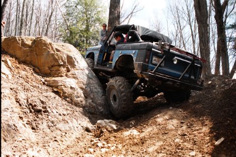 1976 Ford Bronco - A blue 1976 Ford Bronco navigates a challenging rocky trail during an off-road excursion.