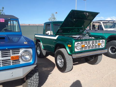 1985 Ford Bronco - Two classic Ford Broncos are parked side-by-side under a clear blue sky.