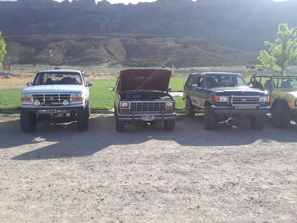 Dark blue SUV with lifted suspension and aftermarket lights, parked in front of mountains