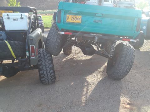 1985 Ford Bronco - A teal Ford truck, likely a 1985 Bronco, is shown from the rear with oversized tires and an Oregon license plate.