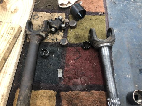 1995 Ford Bronco - Disassembled driveshaft components, including yokes and a universal joint, laid out on a rug.