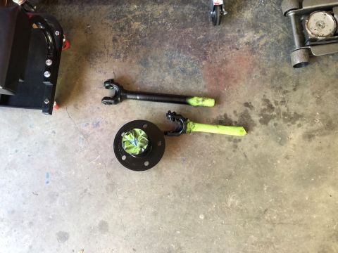 1995 Ford Bronco - Driveshaft and flange parts are laid out on a concrete floor, some sections covered with green tape.