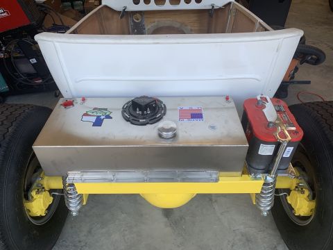 1923 Ford Model T - The rear of a custom vehicle shows a large fuel tank and battery, with yellow suspension parts.