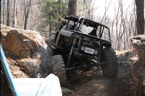 1976 Ford Bronco - Custom buggy navigates a challenging rocky trail in a wooded area.