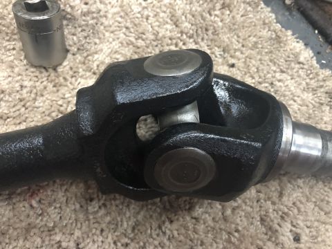 1995 Ford Bronco - A driveshaft universal joint is shown, with a socket tool resting on a carpeted surface.