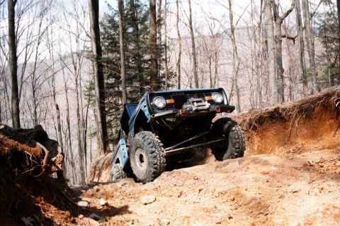 1976 Ford Bronco - This heavily modified off-road vehicle navigates a challenging dirt trail in a wooded area.