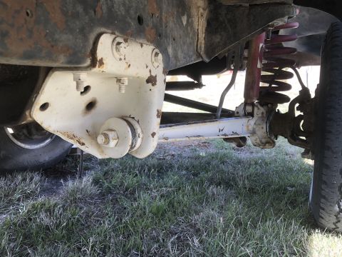 1978 Ford Bronco — Close-up of white painted suspension bracket and red coil spring on a vehicle