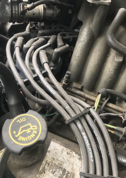 1995 Ford Bronco - Close-up view of an engine bay, showing spark plug wires and an oil cap.