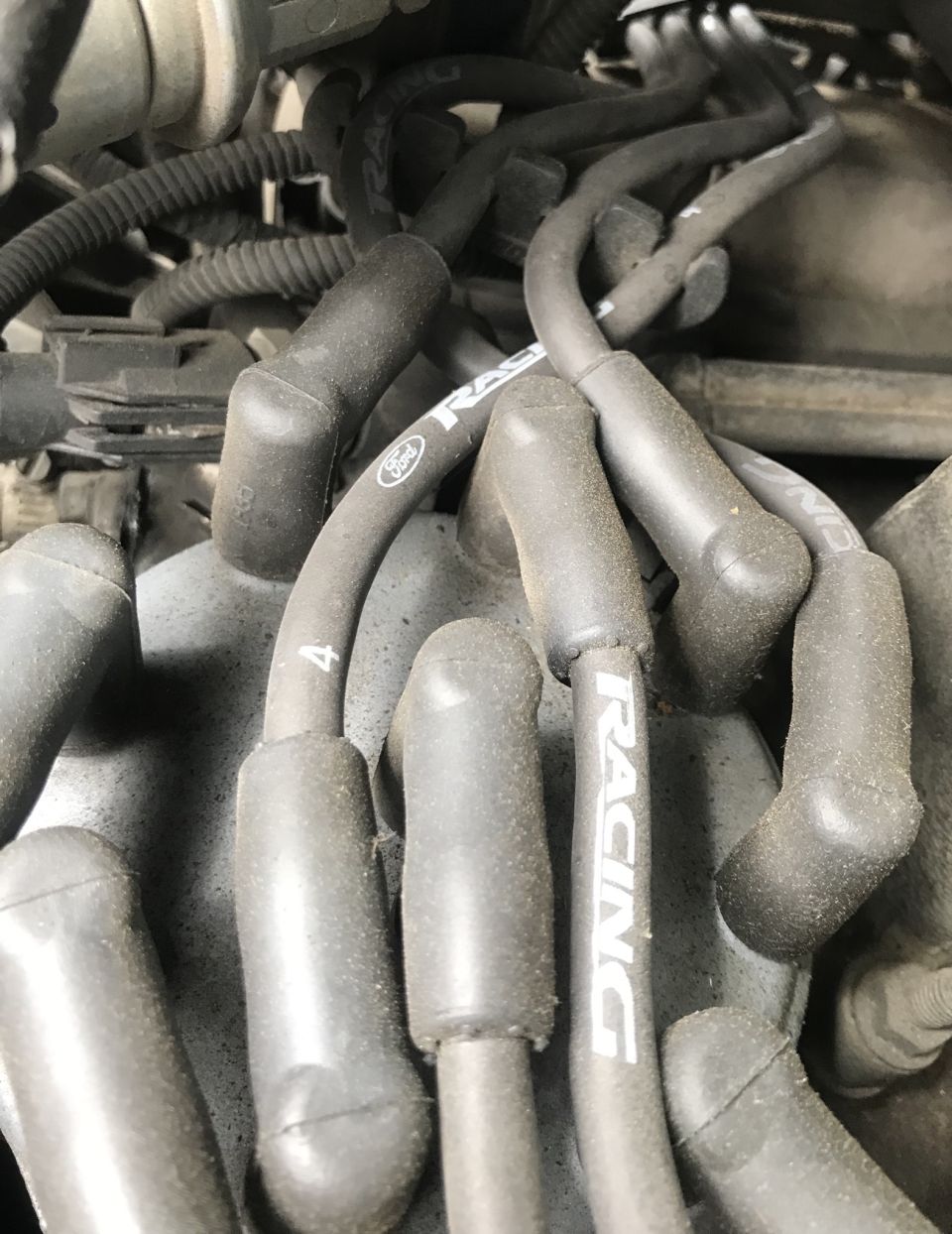 Engine spark plug wires with 'RACING' text and a Ford logo visible on one wire