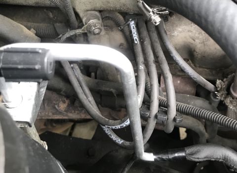 1995 Ford Bronco - Close-up of engine compartment components, including spark plug wires and part of the AC system.