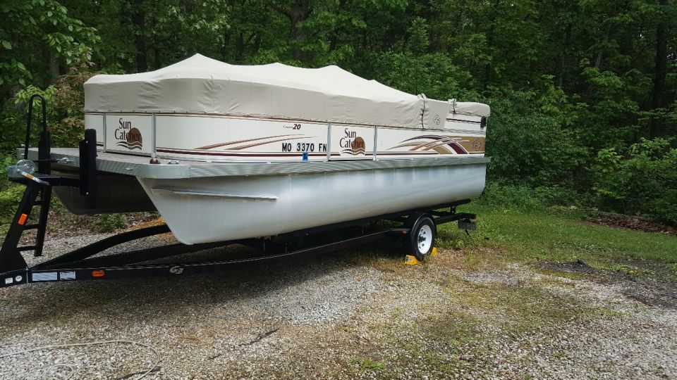 Pontoon boat covered on a trailer, with 'Sun Catcher' logo visible