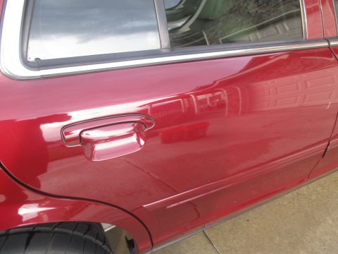 2004 Ford Crown Victoria - Side view of a red 2004 Ford Crown Victoria, showing the door and a tire.