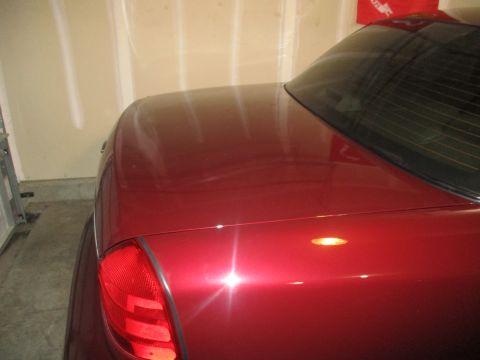 2004 Ford Crown Victoria - Rear view of a red sedan, showing the trunk and taillight area. Supermotors.net logo is present.