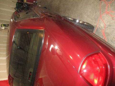 2004 Ford Crown Victoria - The rear of a red 2004 Ford Crown Victoria is visible, showing the taillight and tinted rear window.