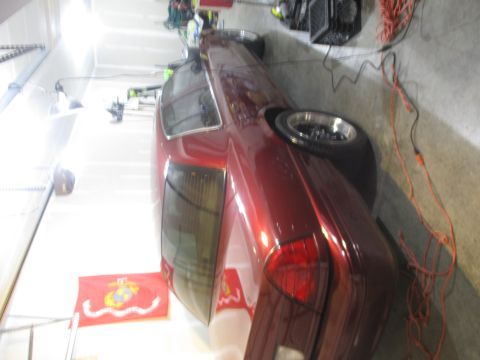 2004 Ford Crown Victoria - A red sedan is parked in a garage, with a US Marine Corps flag visible on the floor.