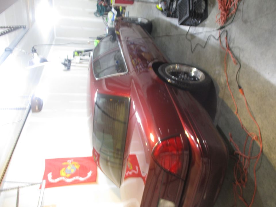 Red sedan parked in a garage, with a US Marine Corps flag on the floor