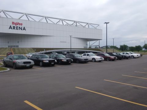 2004 Ford Crown Victoria - Multiple Ford Crown Victoria sedans are parked in a lot outside the Hy-Vee Arena.