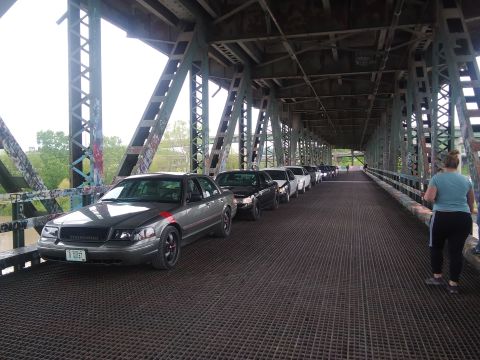 2004 Ford Crown Victoria - A line of Ford Crown Victorias are parked on a bridge under a metal structure.
