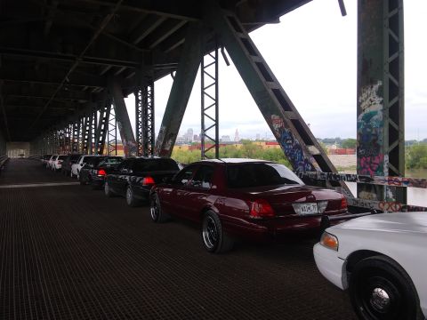 2004 Ford Crown Victoria - A line of Ford Crown Victorias are parked on a bridge under a metal structure.