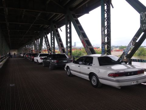 2004 Ford Crown Victoria - A line of Mercury Grand Marquis sedans are parked on a bridge, with the lead vehicle in white.