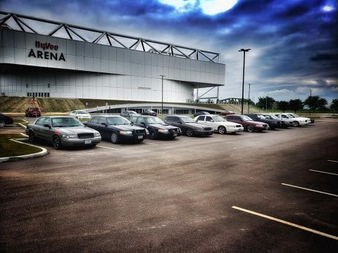 2004 Ford Crown Victoria - A line of Ford Crown Victoria sedans, including police models, are parked outside the Hy-Vee Arena.