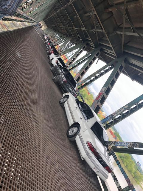 2004 Ford Crown Victoria - Multiple vehicles lined up on a bridge, including a white 2004 Ford Crown Victoria.