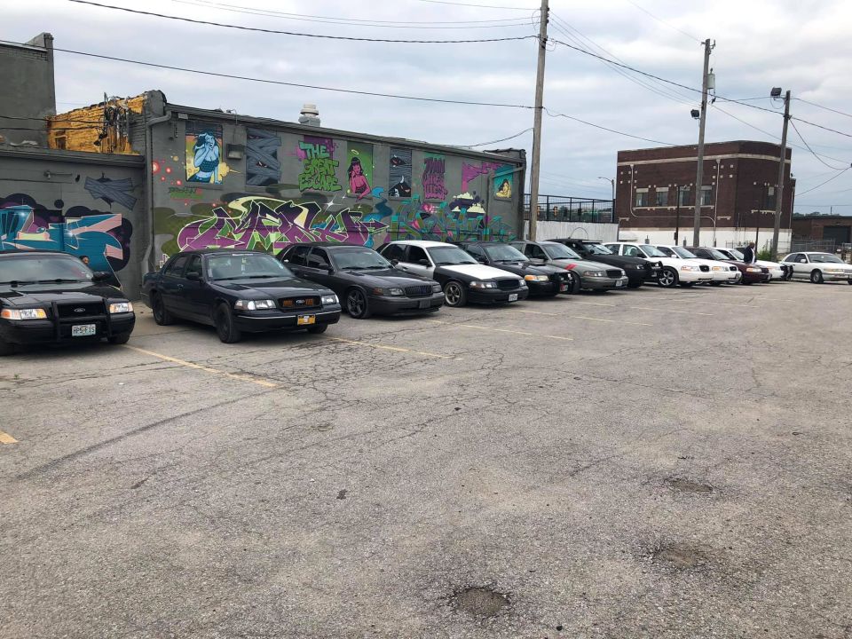 Several black police sedans parked in a lot, one has a license plate that reads BPG831