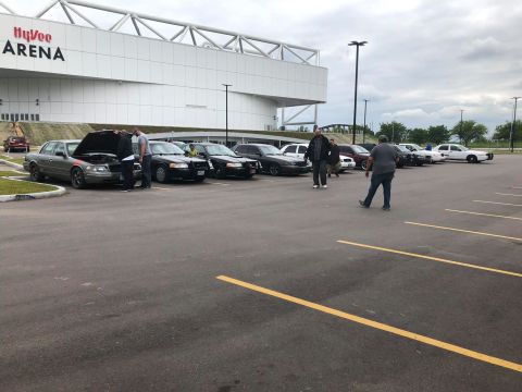 2004 Ford Crown Victoria - Several Ford Crown Victorias are parked in a lot outside a large arena.