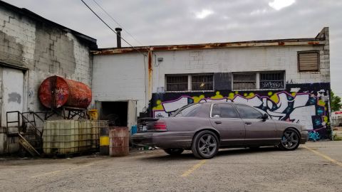 2004 Ford Crown Victoria - A 2004 Ford Crown Victoria is parked outside a building with graffiti on the wall.