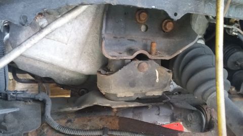 Engine mount with visible cracks and rust, part of a vehicle's undercarriage