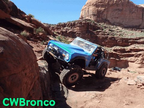 1995 Ford Bronco - An off-road SUV drives through a rocky desert landscape.